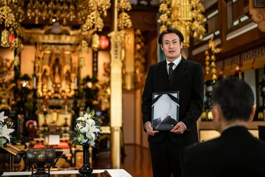 遺影を持つ男性