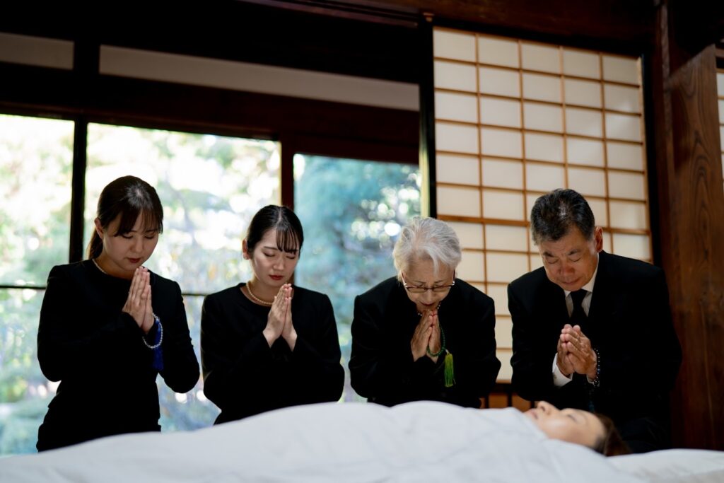 手を合わせる遺族