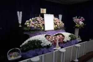 白と紫の花で飾られた葬儀の祭壇と遺影