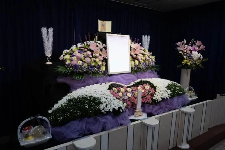 白と紫の花で飾られた葬儀の祭壇と遺影