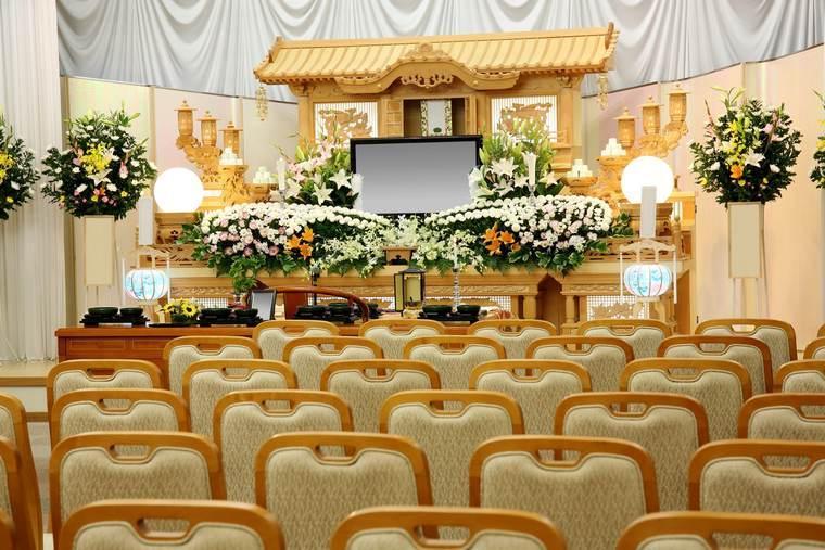 椅子が並ぶ生花祭壇の葬儀式場