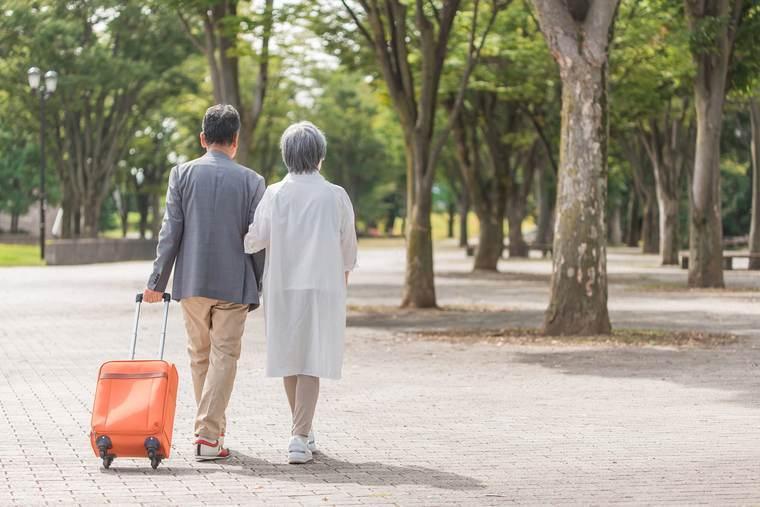 スーツケースを引いて歩く高齢の夫婦