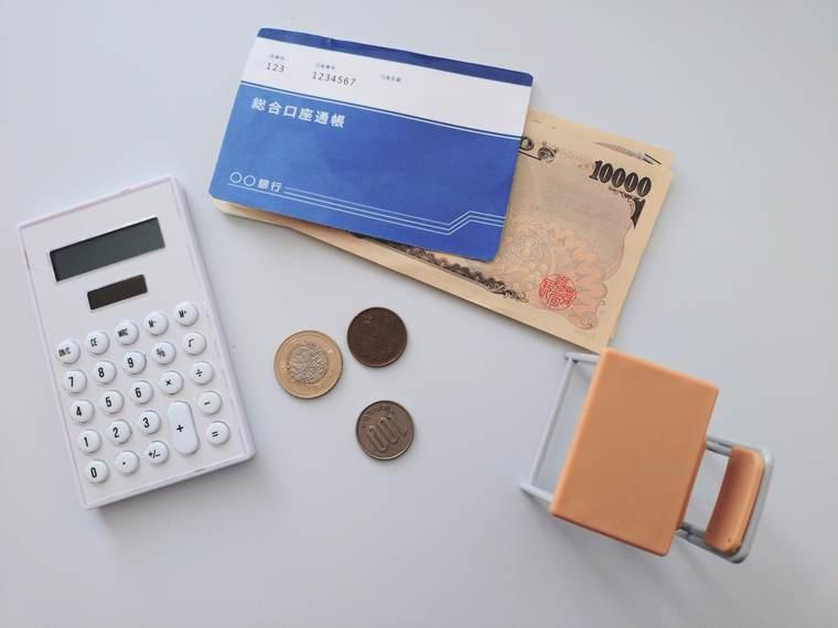 預金通帳と一万円札と電卓