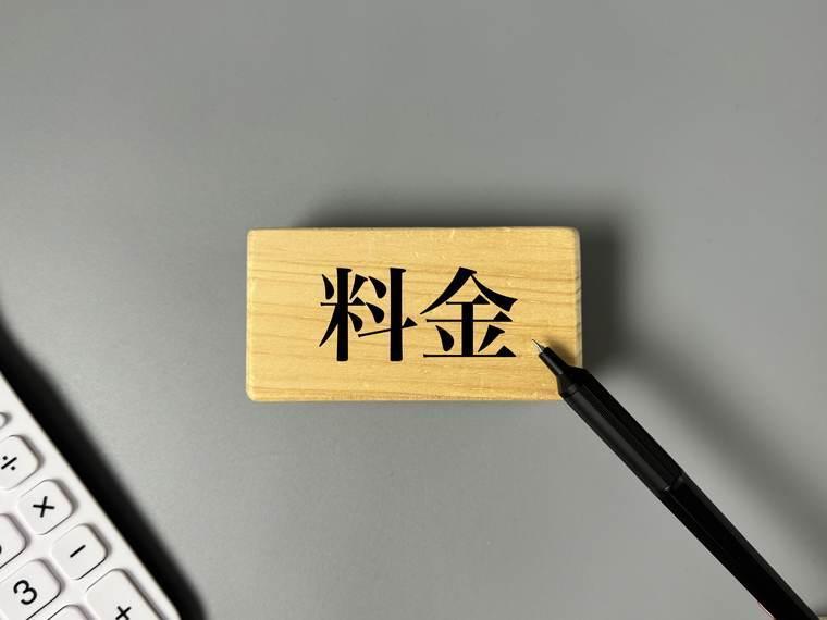 「料金」と書かれた木札と電卓とペン