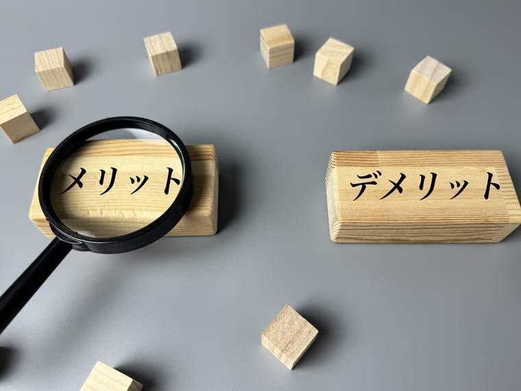 「メリット」「デメリット」と書かれた木札と虫眼鏡