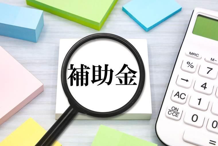 「補助金」と書かれた紙と虫眼鏡と電卓