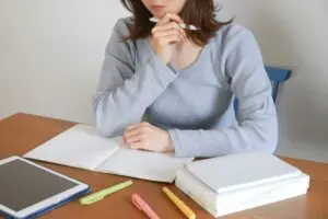 ノートを前に考え込む女性のイメージ